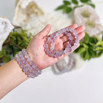 light amethyst round bead bracelet on a wrist and some in a hand