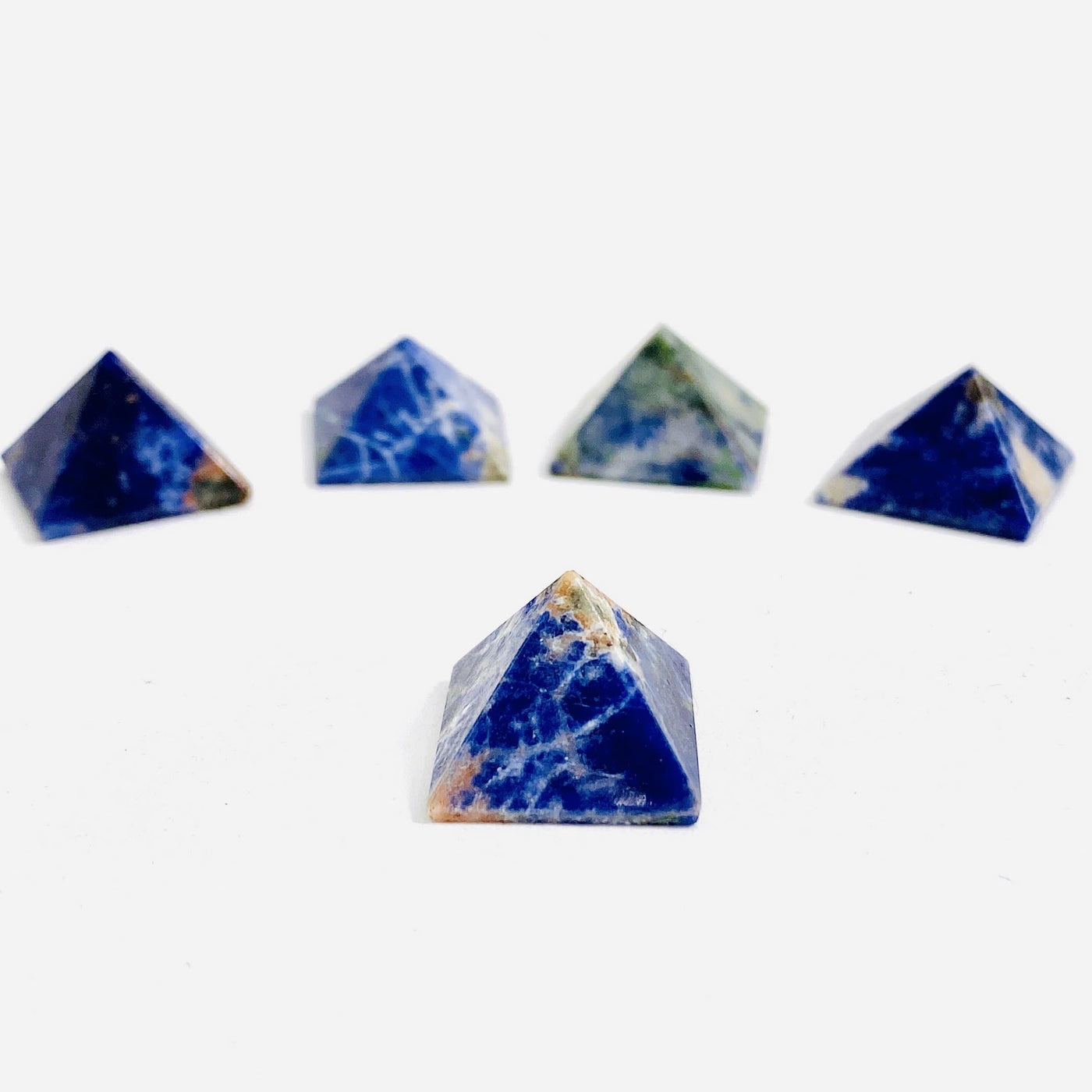 close up of one sodalite small pyramid on white background with four others in background