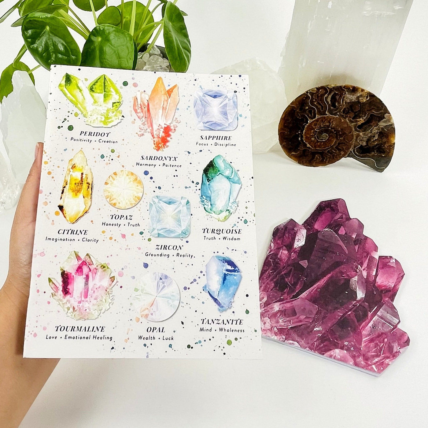 hand holding up Crystal Journal with decorations in the background