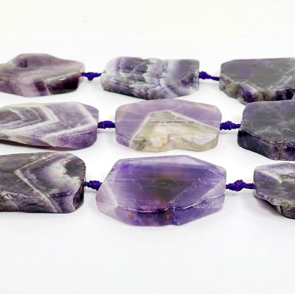 Chevron Amethyst slab beads - Polished Beads--front close view of detail and tones of stones on table.