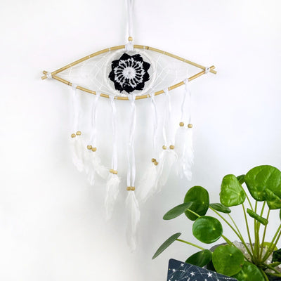 White Dream Catcher with Black All Seeing Eye Pattern with white ties and white feather ends on white background