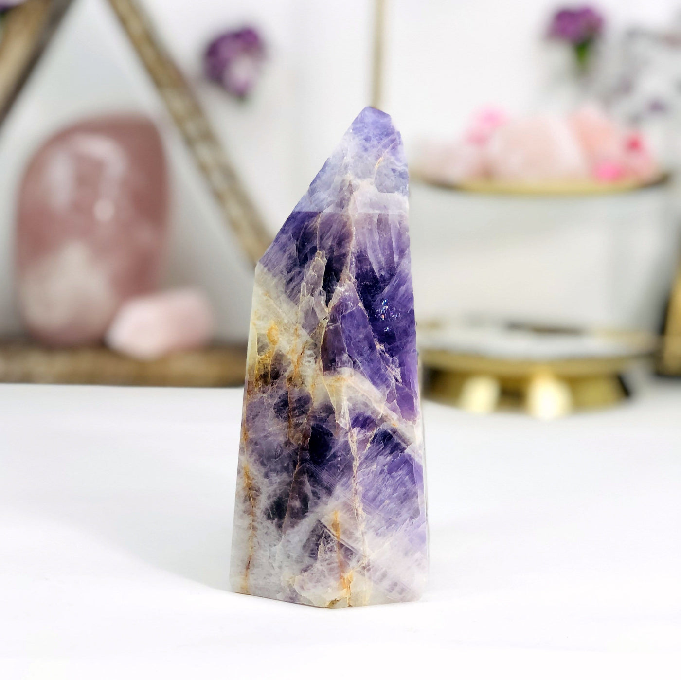 side view of Chevron Amethyst Polished Point with decorations blurred in the background