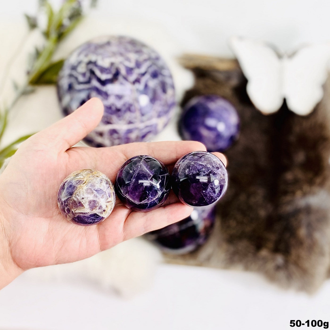 Chevron Amethyst Polished Spheres in a hand, size under 50g-100g