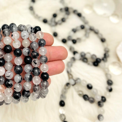 Black Rutilated Round Bead Bracelets - a group in a hand