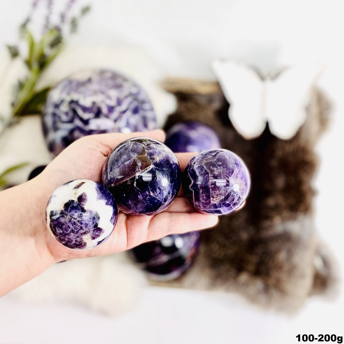 Chevron Amethyst Polished Spheres in a hand, size under 100-200g