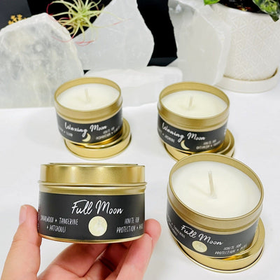 hand holding up full moon phase candle with others in the background