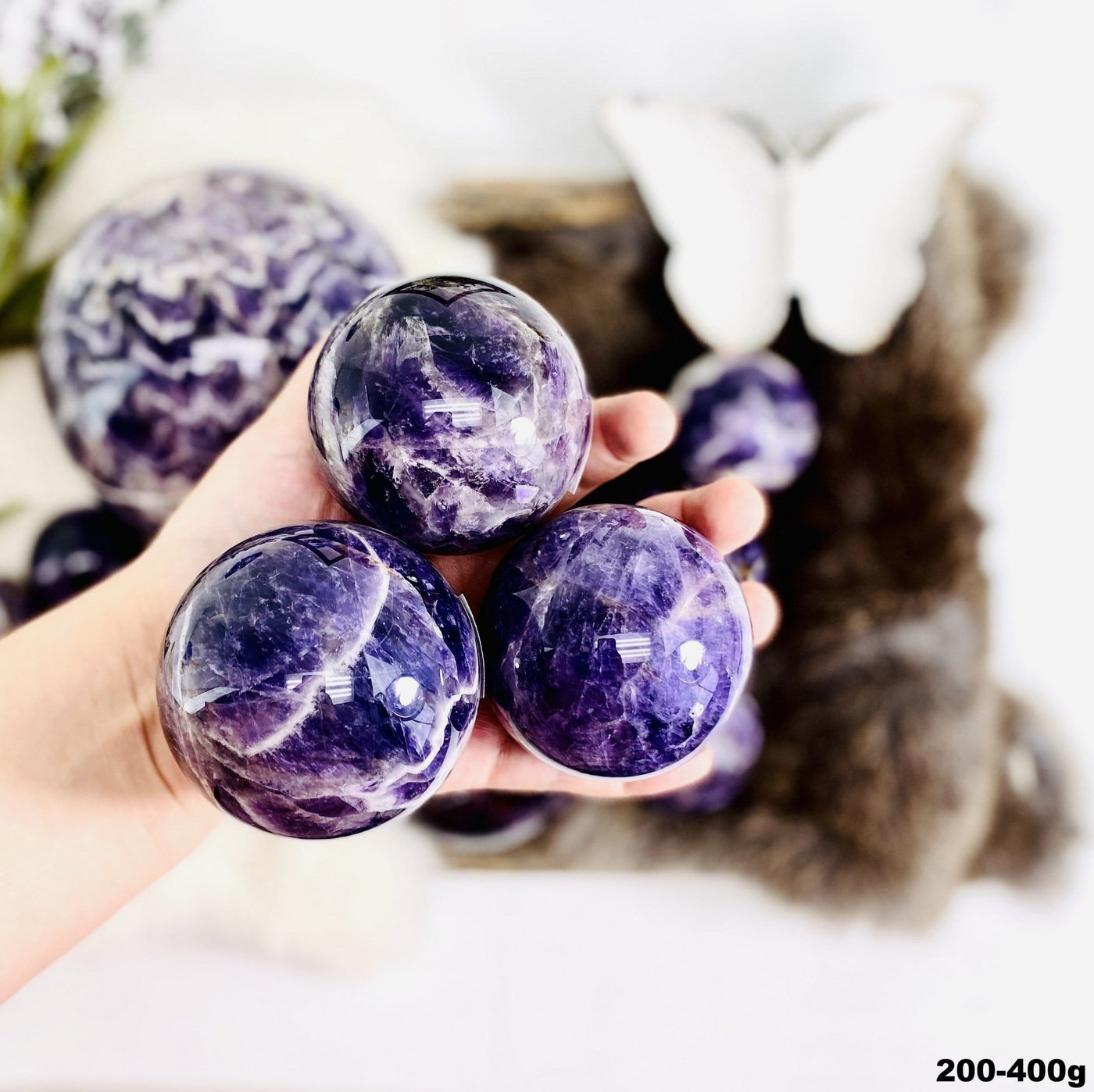 Chevron Amethyst Polished Spheres in a hand, size under 200-400g