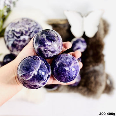 Chevron Amethyst Polished Spheres in a hand, size under 200-400g