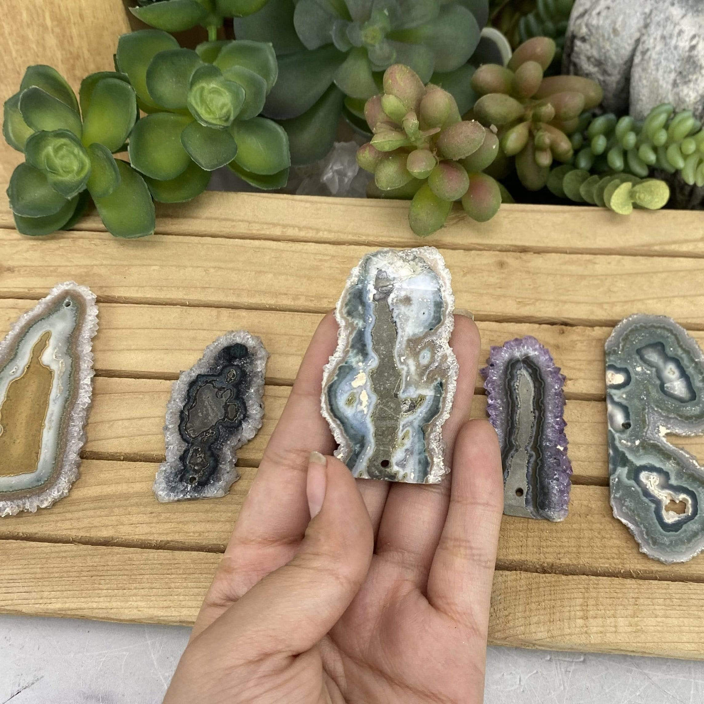 hand holding up Drilled Stalactite Slice with others in the background