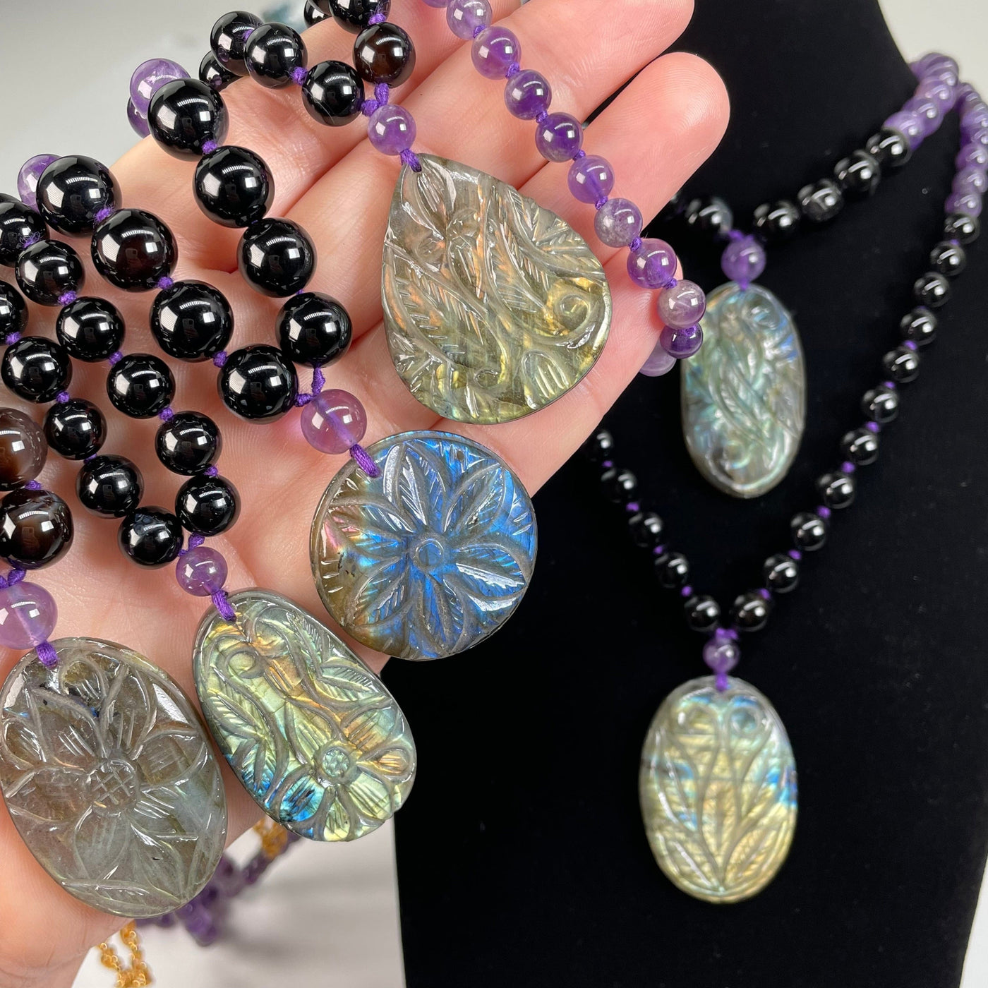 multiple labradorite pendants in hand to show that each one has a different engraved design 