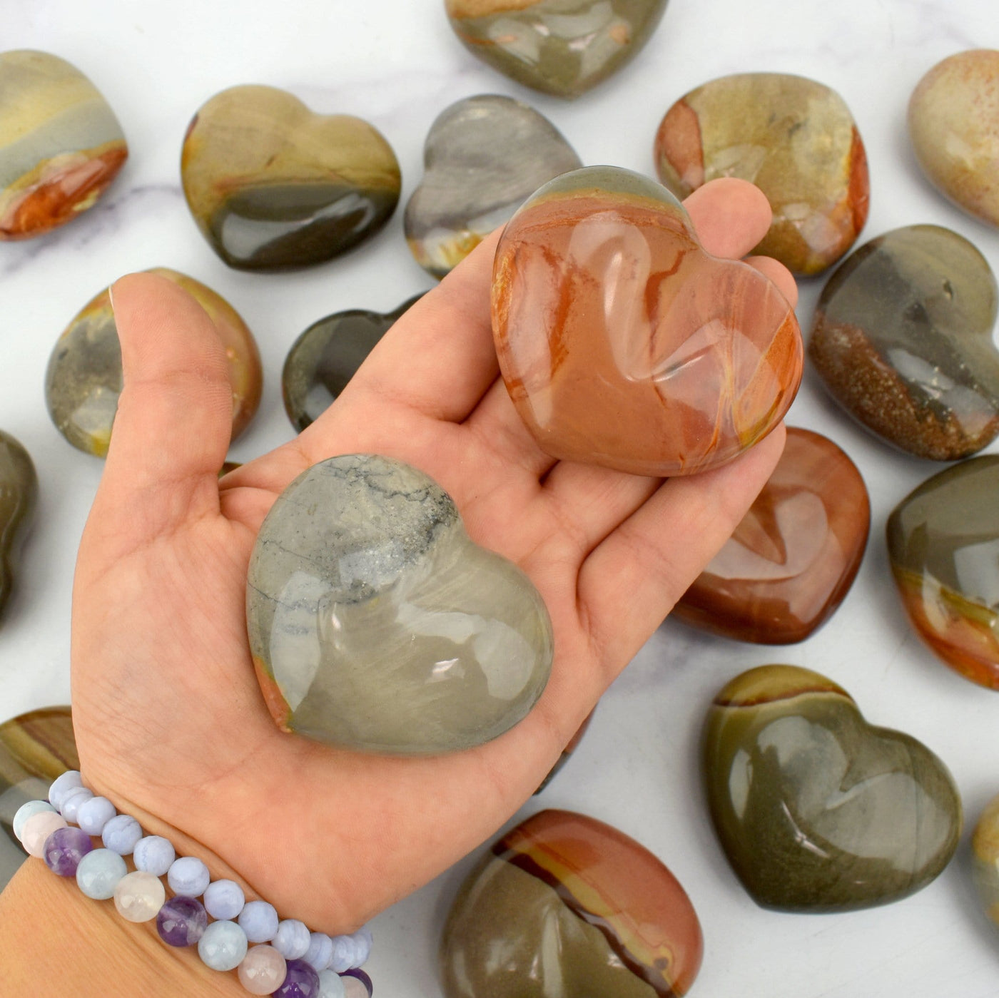 Hand holding 2 Polychrome Jasper Polished Hearts For Size Reference and Close up 
