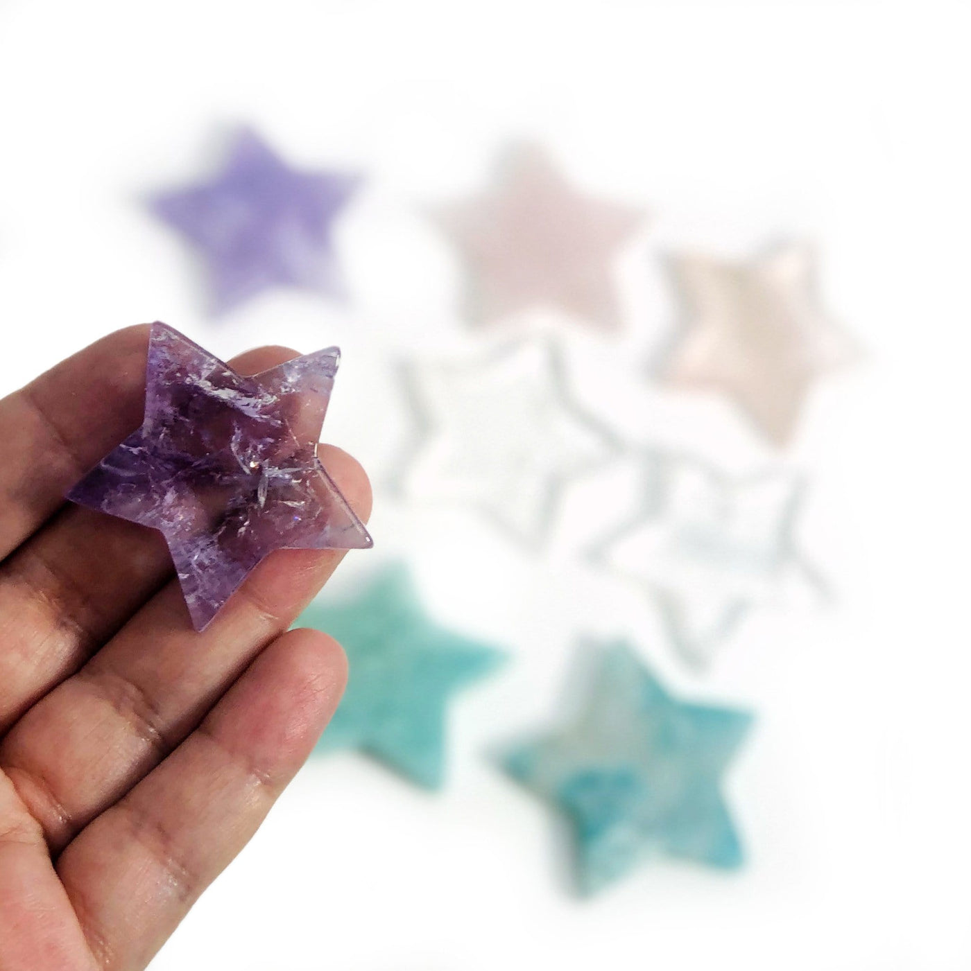 hand holding up amethyst Products Gemstone Star Cabochon with others blurred in the background