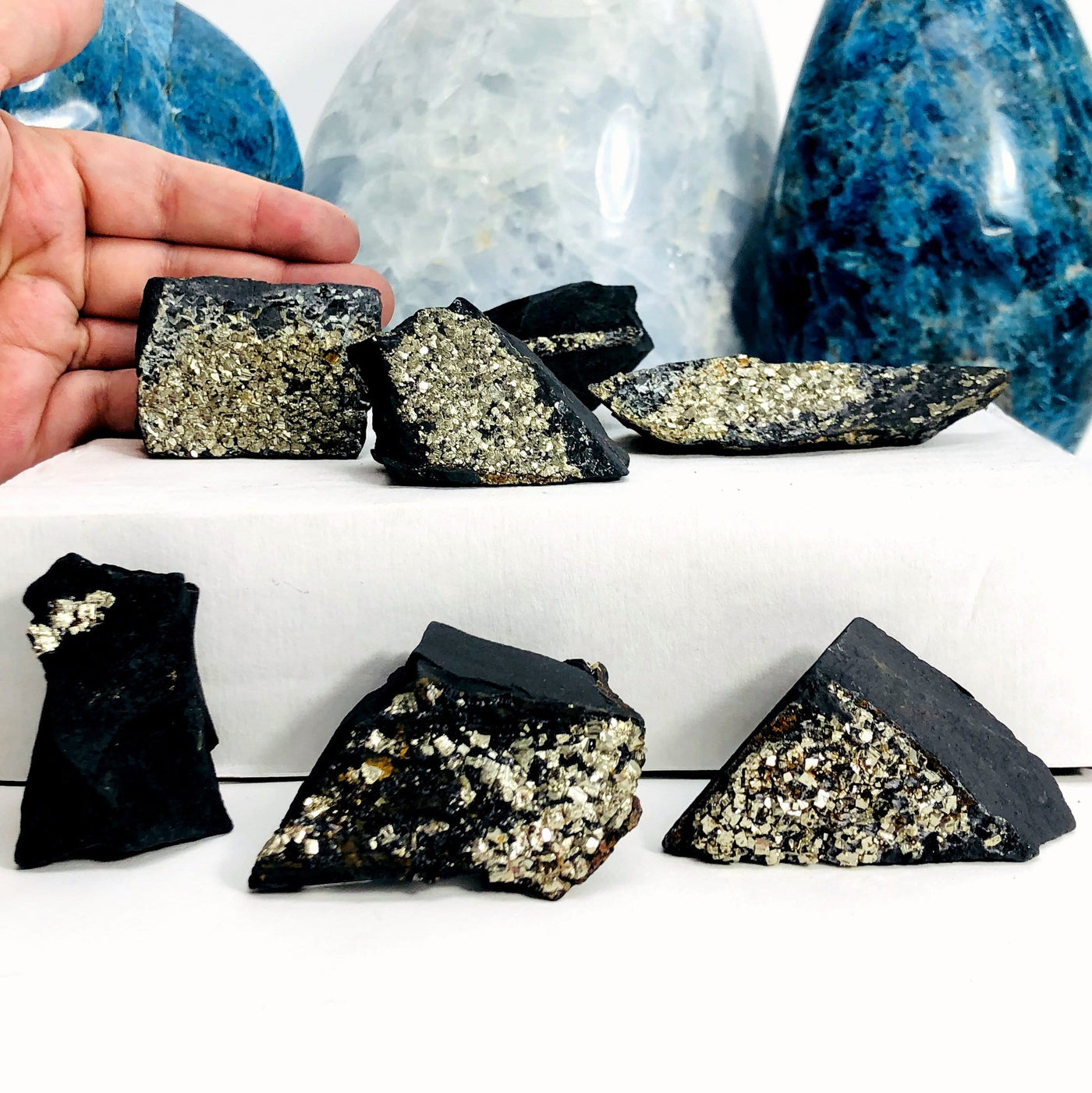 hand behind Pyrite on Basalt Matrix Chunks with decorations in the background
