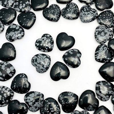 overhead view of five snowflake obsidian hearts in a star formation in the center with many others filling the perimeter 