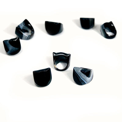 8 Black Agate Cat Polished Rings placed spread out to show difference in color tones 