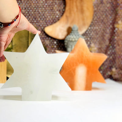 white selenite star lamp in hand for size reference with orange selenite star lamp in background
