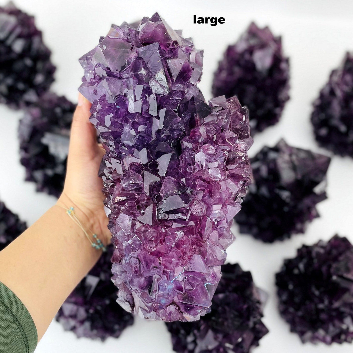 large purple salt crystal formation in hand for size reference