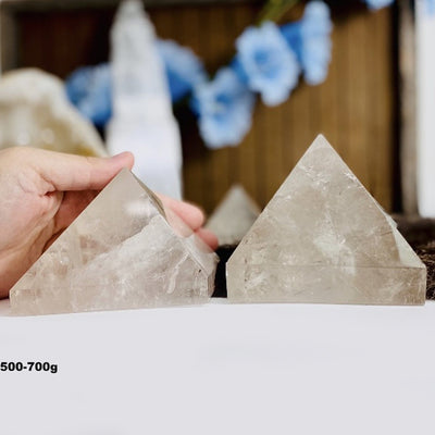 hand holding 500-700g Crystal Quartz Pyramid with decorations blurred in the background