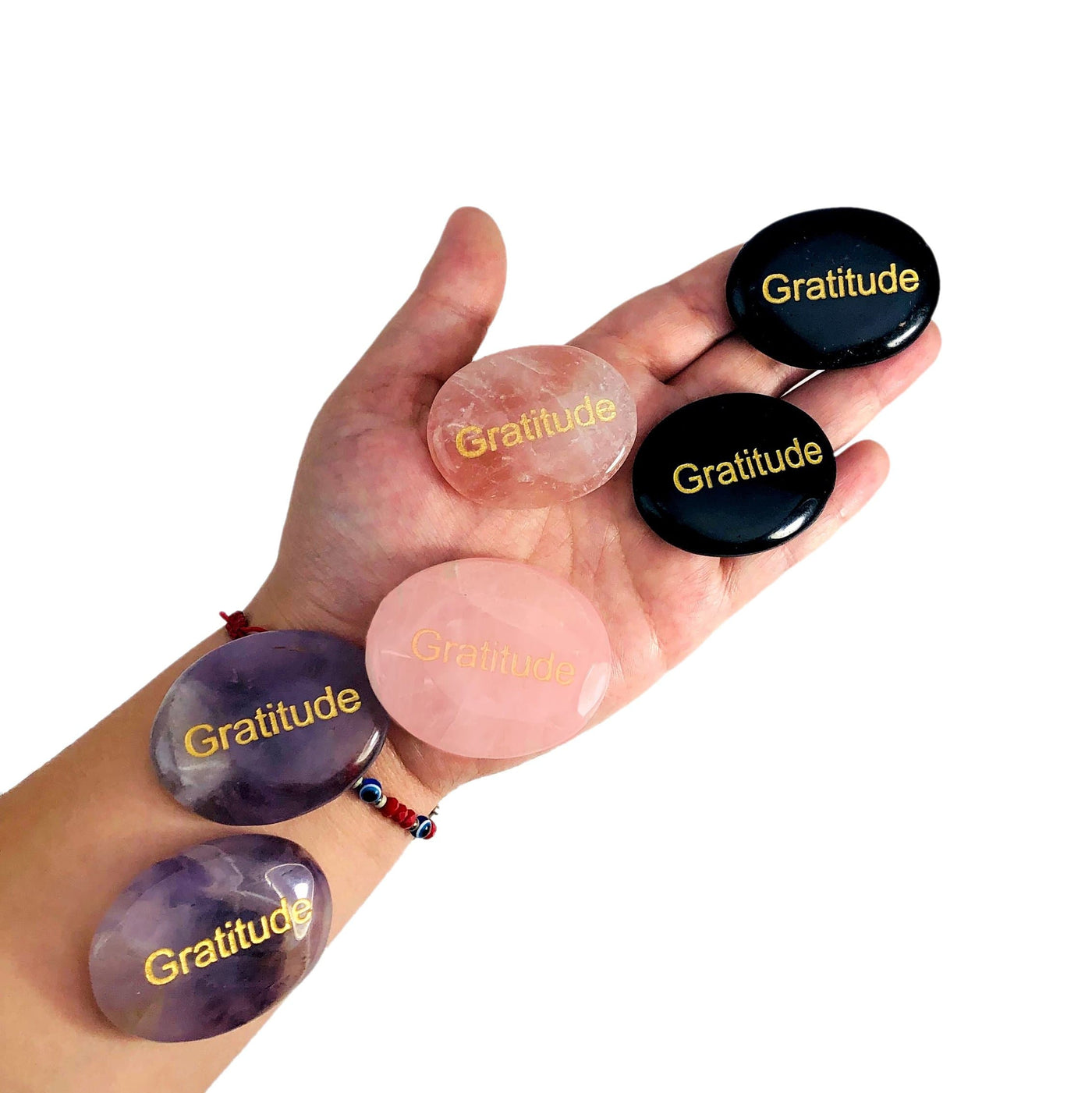 Pocket Stone "Gratitude" Palm Stones, two of each kind, laid out on woman's hand and arm.