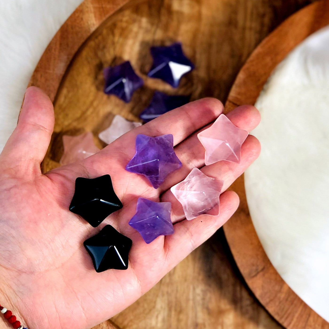 Six Puffy Star Cabochon Gemstones displayed in hand, black, purple and pink - two of each.
