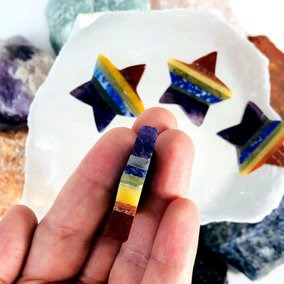 side view of seven chakra star in hand for thickness with three others laying flat in background
