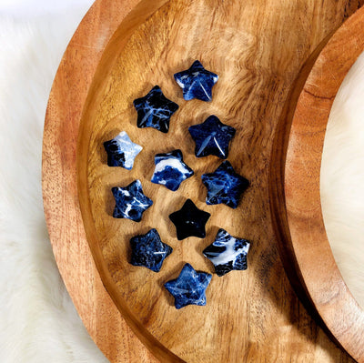 11 Blue Sodalite Puffy Star Cabochon Gemstones displayed on a wooden moon shaped tray.