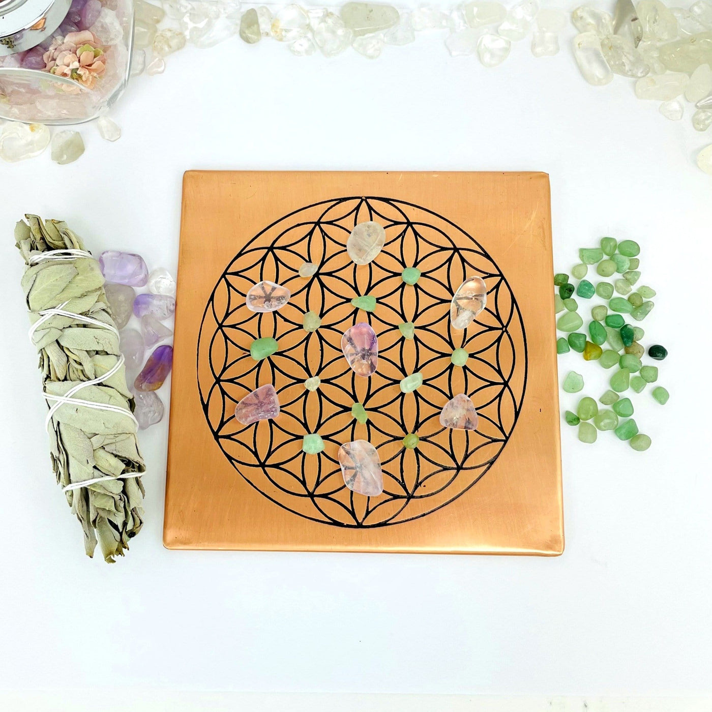 copper square flat plate with a flower of life grid in black on it displayed with assorted crystals on the grid
