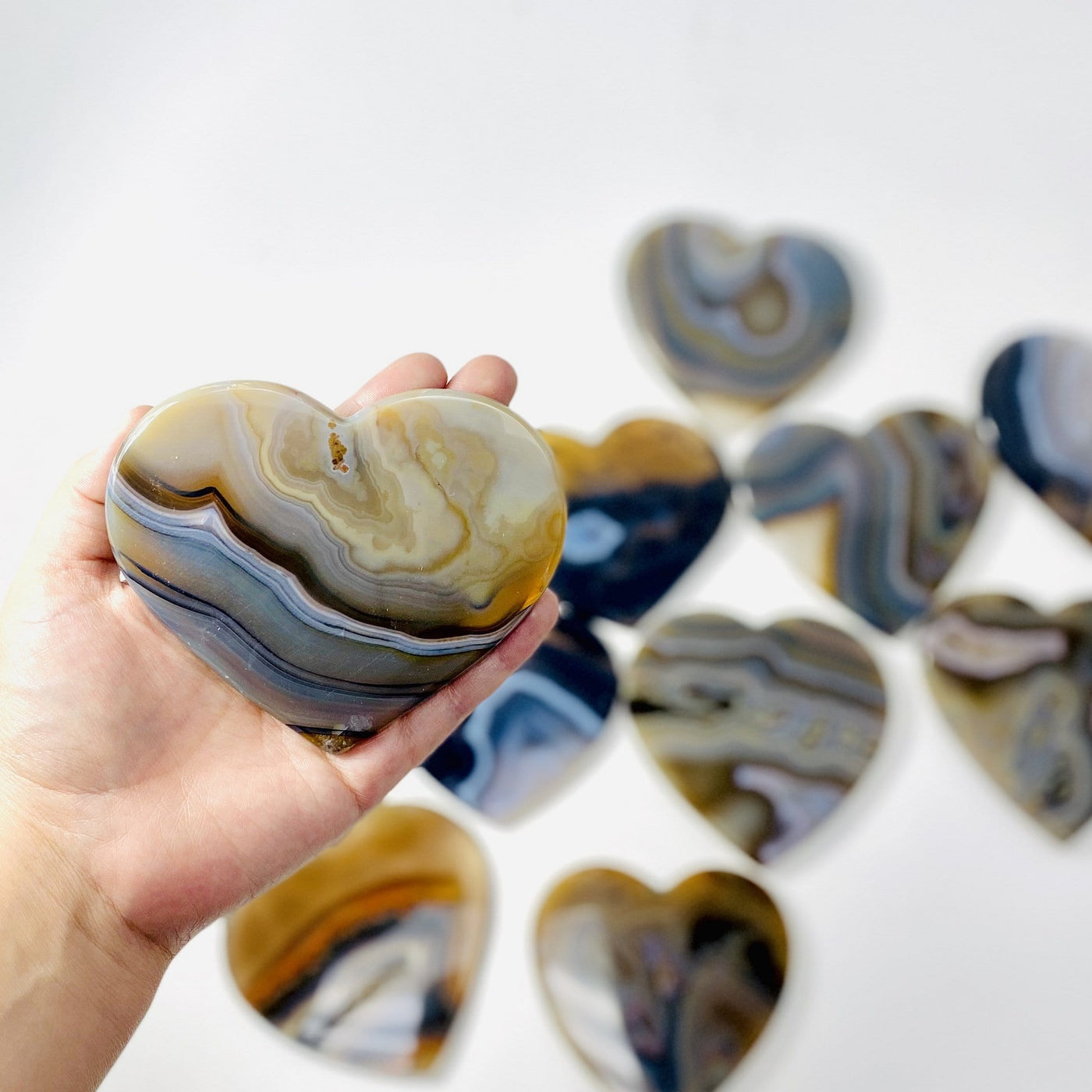 Natural Agate Heart Slice held in hand while others remain out of focus
