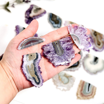 hand holding up 4 different amethyst stalactites with others blurred in the background