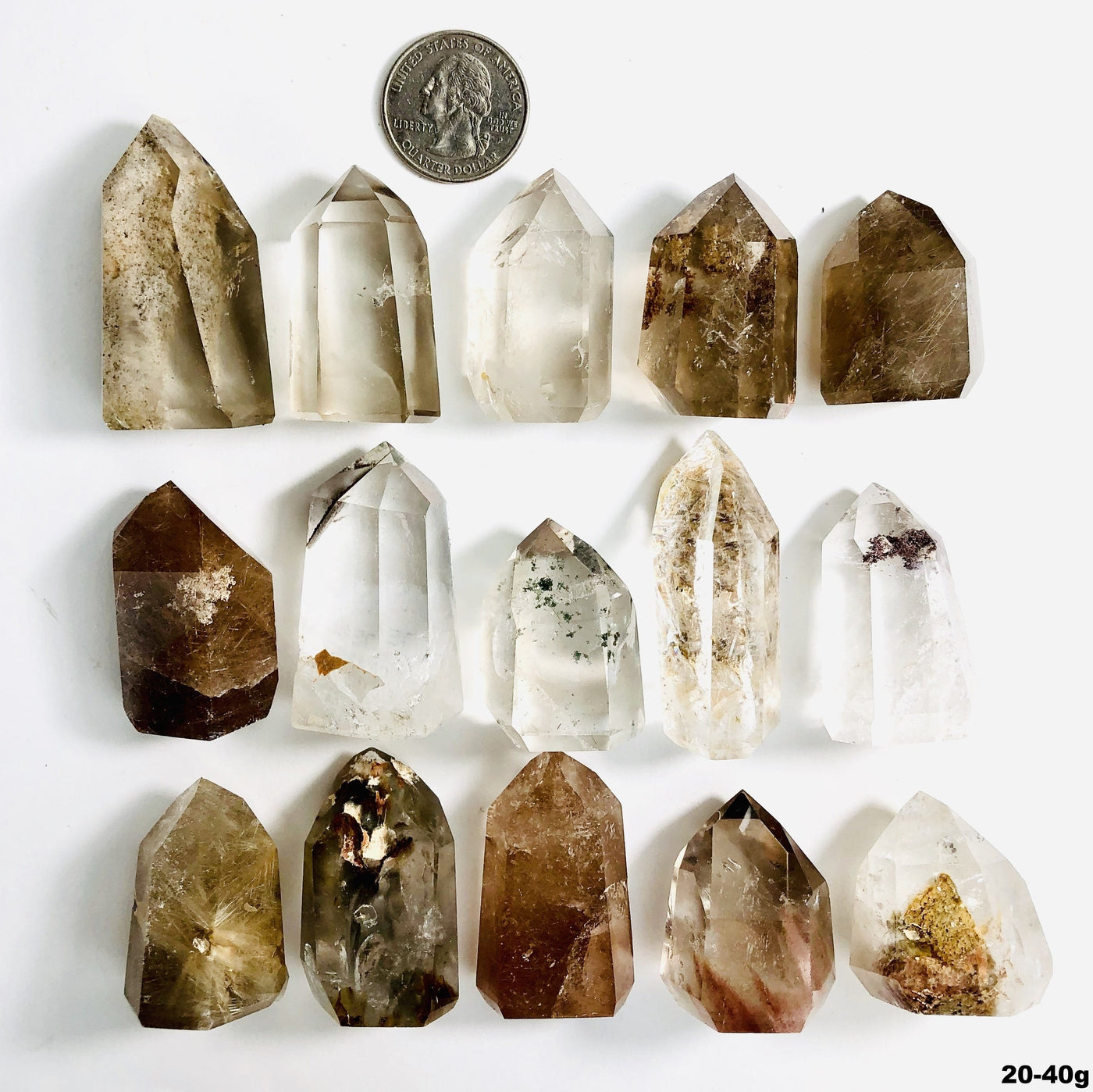 15 crystal points with inclusions next to a quarter for size reference on white background