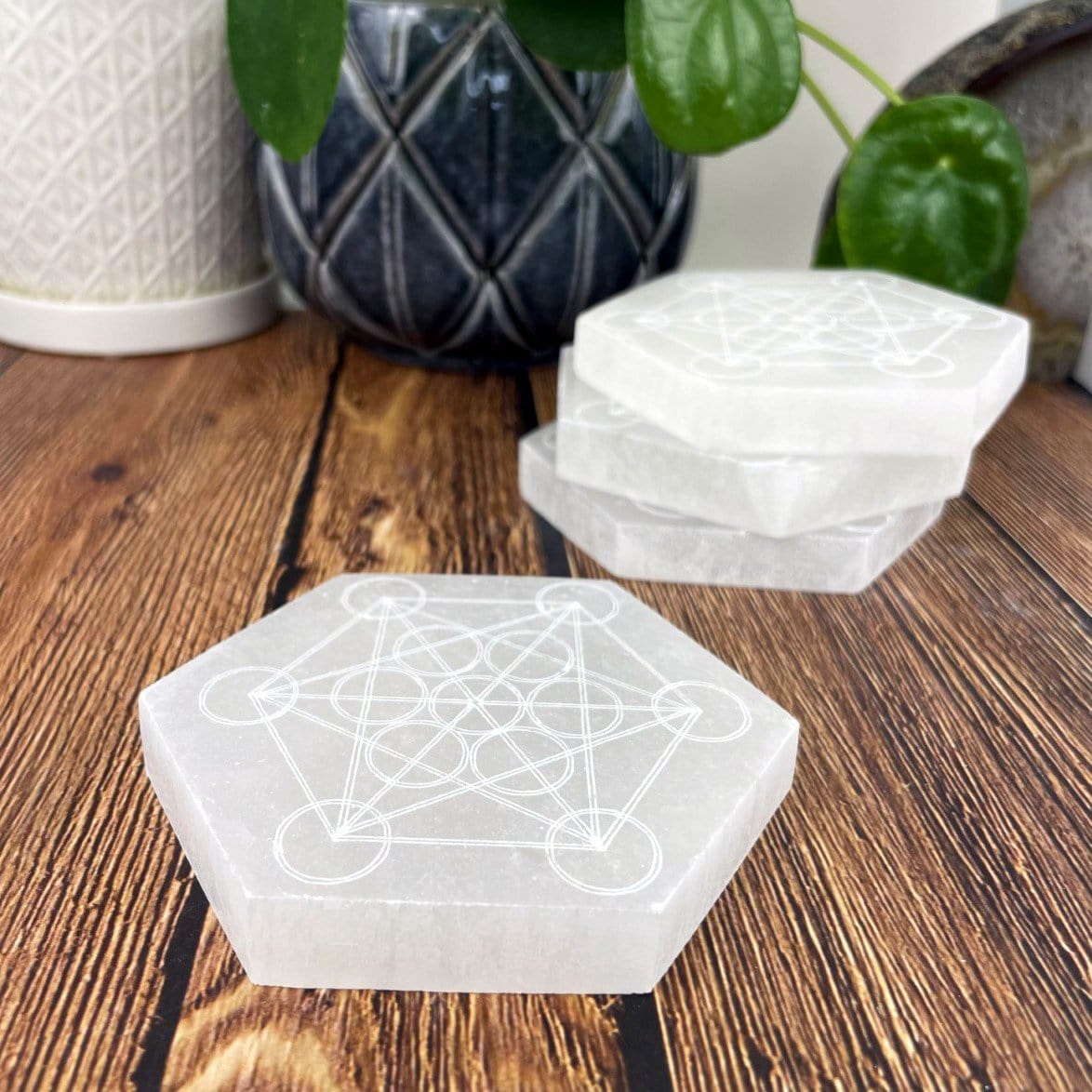 angled view of selenite hexagon engraved with metatron symbol with others in background for thickness
