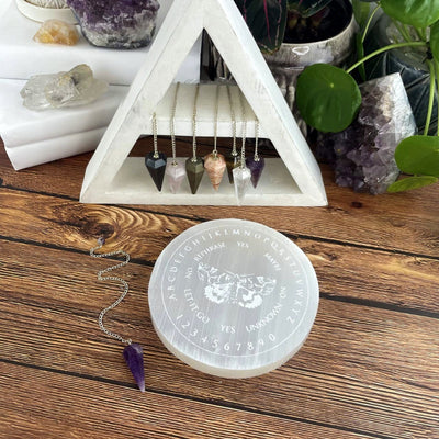 selenite moth pendulum board engraved charging plate on display with pendulums 
