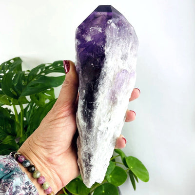 large elestial amethyst point in a woman's hand