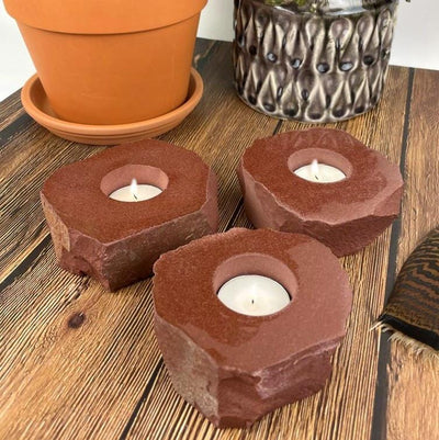 3 rough stone candle holders with decorations in the background