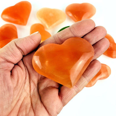 Hand holding a Orange Selenite Puffy Heart