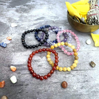 Chakra Bracelet Set - 7 Mala Bead Bracelets scattered on a table