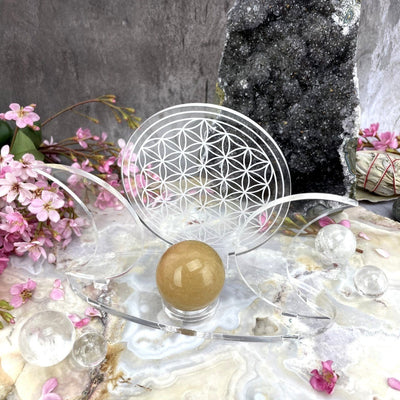 Acrylic Sphere Holder Crescent Moons - Flower of Life holding a sphere in an alter that consists of crystals and flowers.