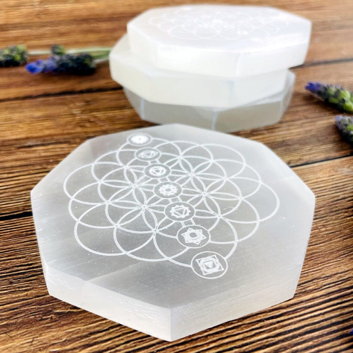angled view of selenite hexagon engraved with flower of life chakras for thickness