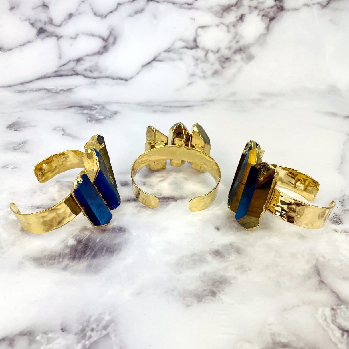 3 Titanium Crystal Quartz Triple Point Cuff Bracelet with Electroplated 24k Gold on marble background