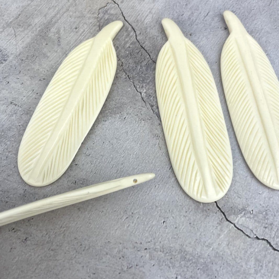 Large Bone Feather Bead  - 3 on a table