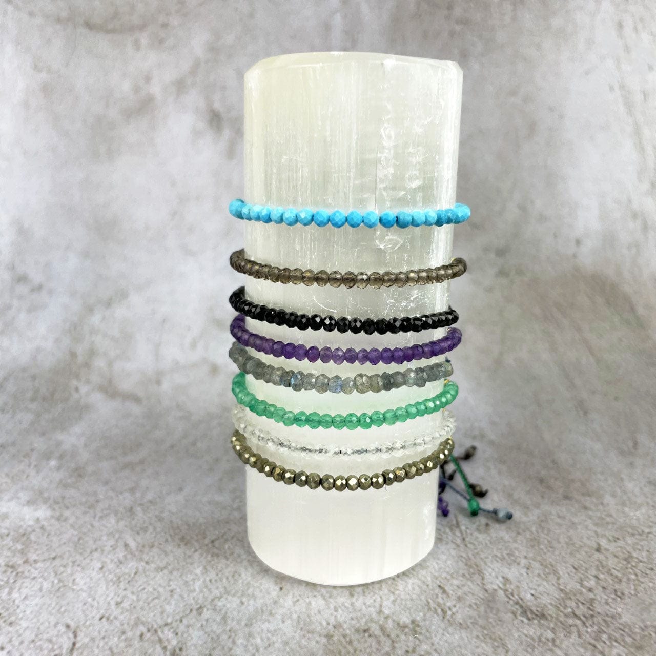Gemstone Bracelet - Adjustable Cord with Gold Plated over Sterling Silver Beads one of each stone available, pyrite, moonstone, green onyx, labradorite, amethyst, black spinel, smoky quartz, and chinese turquoise on a stand