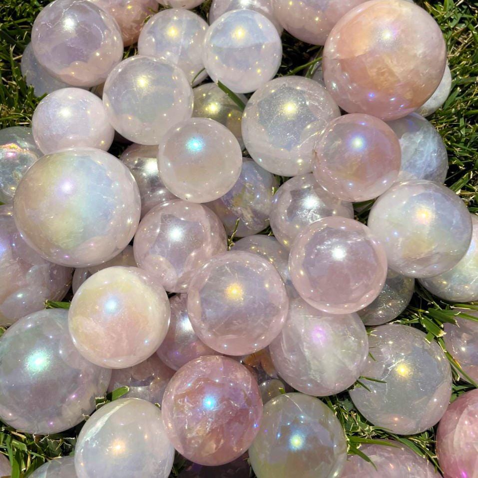 Pile of Rose Quartz Angel Aura Titanium Spheres on grass