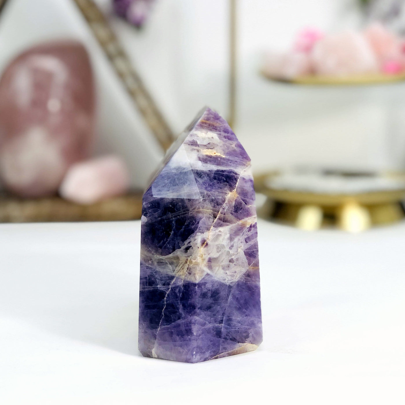 side view of Chevron Amethyst Polished Point with decorations in the background