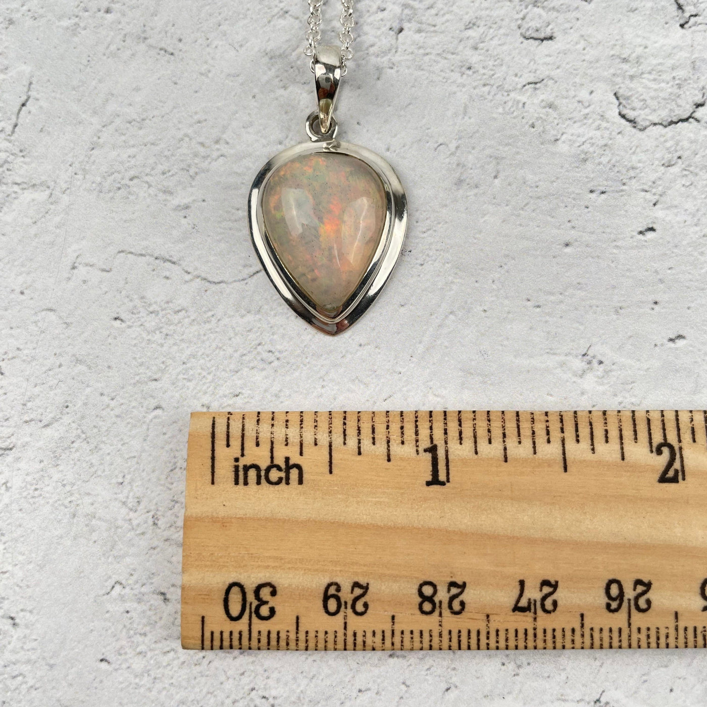 opal pendant displayed next to a ruler for size reference 