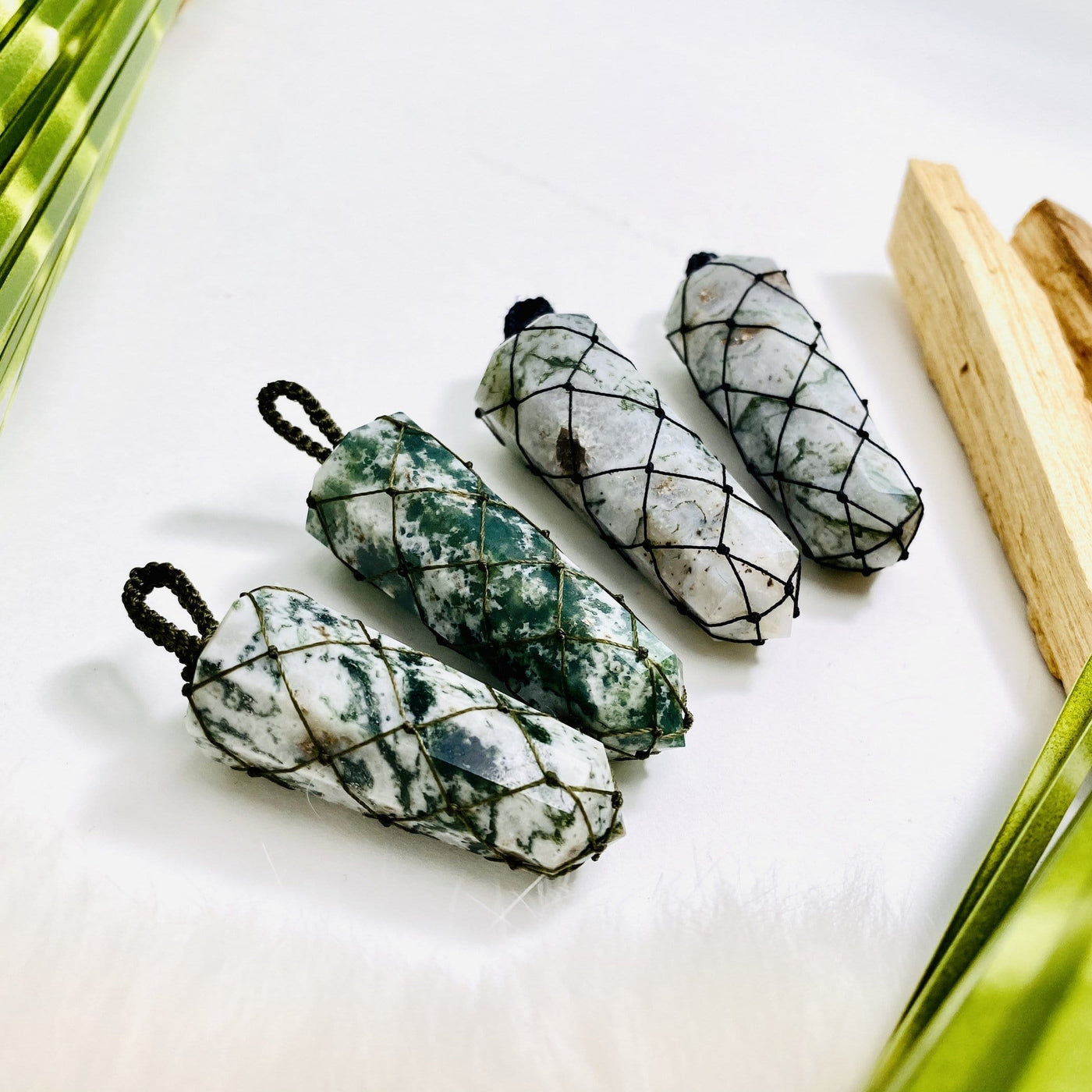 4 moss agate netted pendants with decorations in the background