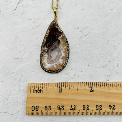 pendant next to a ruler for size reference 