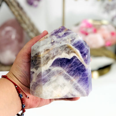hand holding up Chevron Amethyst Polished Point with decorations in the background
