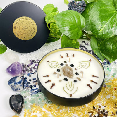Root Chakra Candle Tin displayed with crystals and plants