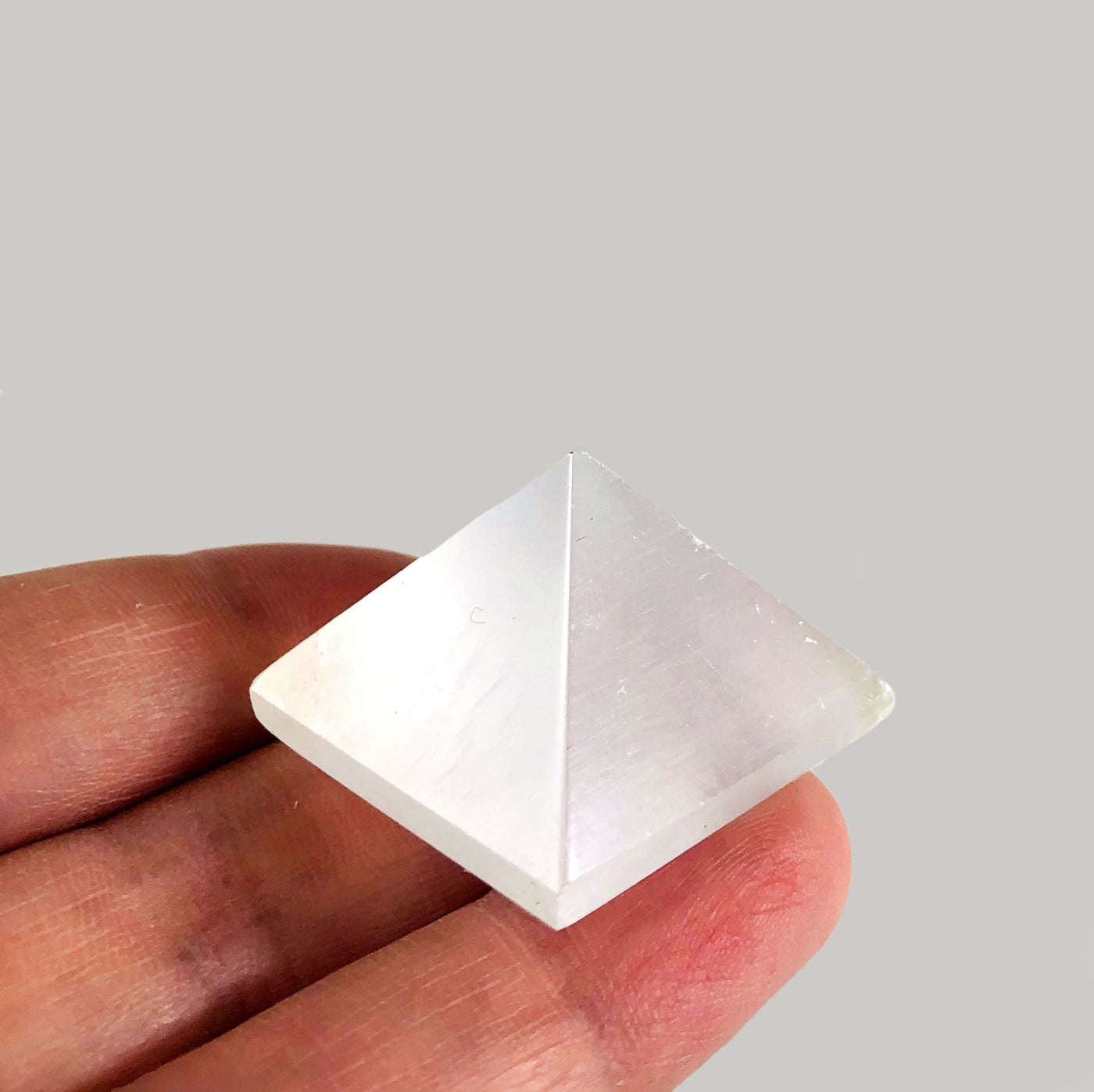 selenite pyramid in hand for size reference