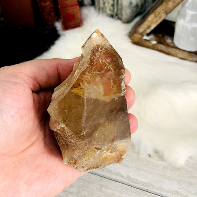 side view of smokey quartz raw point in hand for thickness